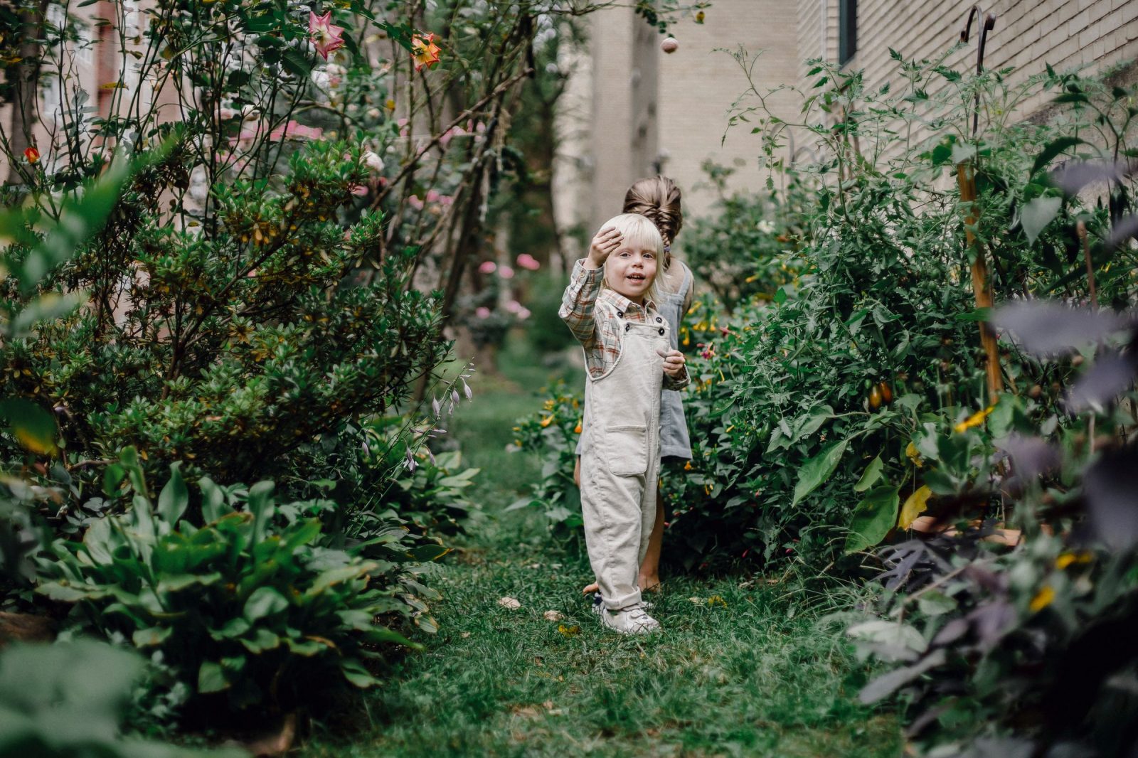 Due bambini giocano nel giardino recintato di una casa di famiglia durante uno scambio vacanze