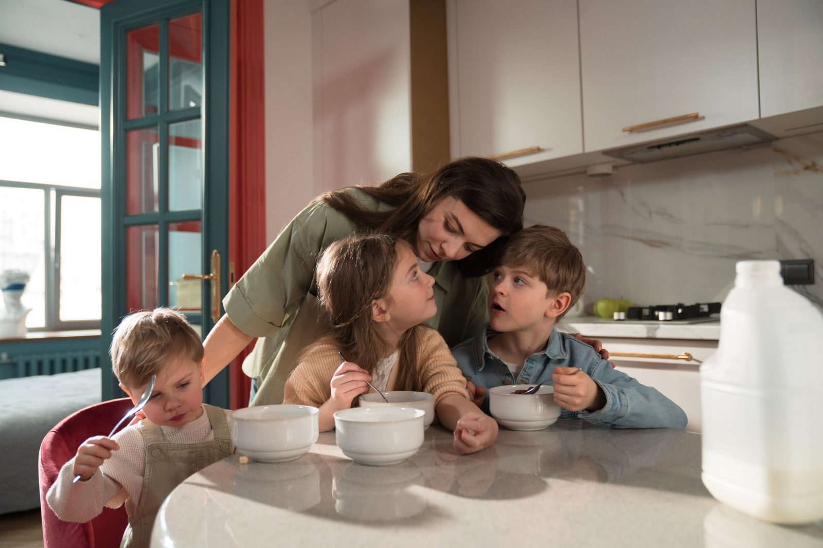 Una madre e i suoi tre bambini fanno colazione nella cucina di una casa in scambio